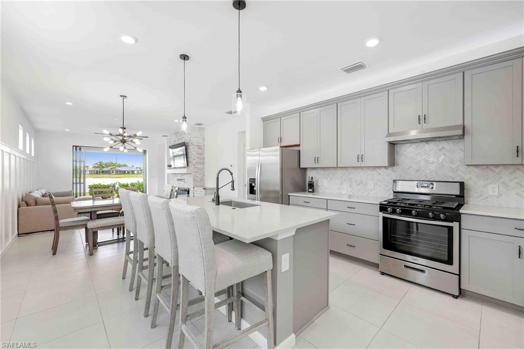 2179 Yellowfin Circle Naples, FL 34114 - Photo 4 of 20 a kitchen with stainless steel appliances kitchen island granite countertop a stove a sink a dining table and chairs