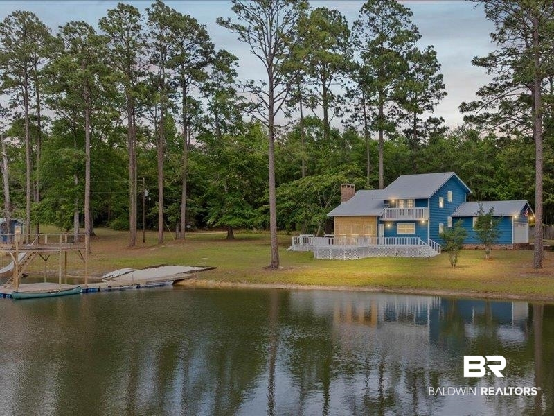 3160 Old Castleberry Road Brewton, AL 36426 - Photo 31 of 36 Waterfront property featuring a blue-sided residence with a metal roof, an expansive deck, upper balcony, and a multi-level dock structure