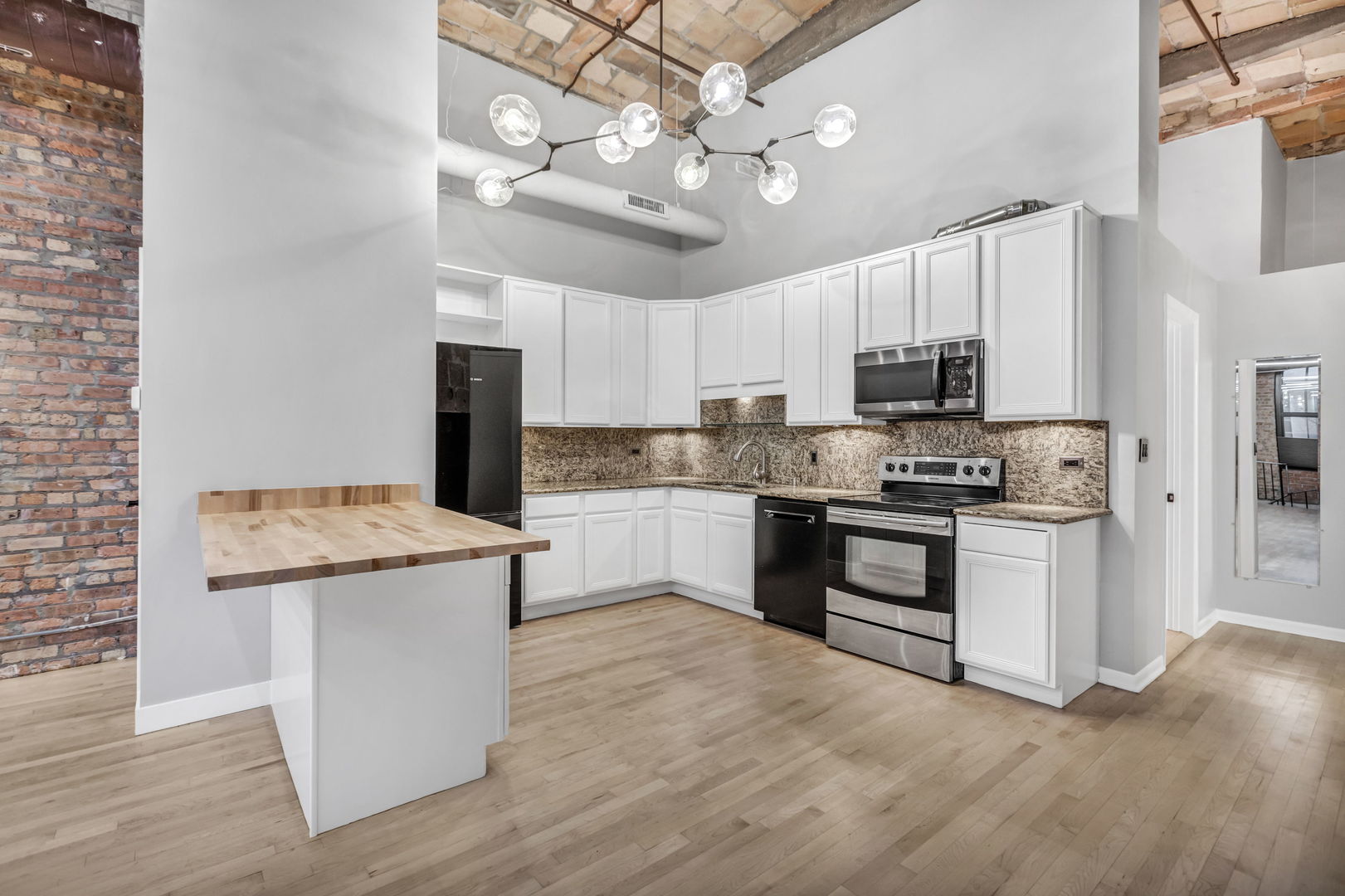 801 South Wells Street, Unit 101 Chicago, IL 60607 - Photo 6 of 33 a kitchen with kitchen island granite countertop a stove top oven a refrigerator cabinets and wooden floor