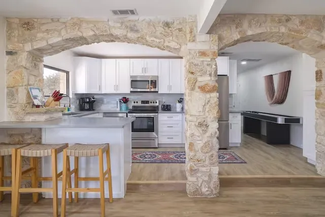 a kitchen with kitchen island granite countertop a stove top oven a sink and a microwave