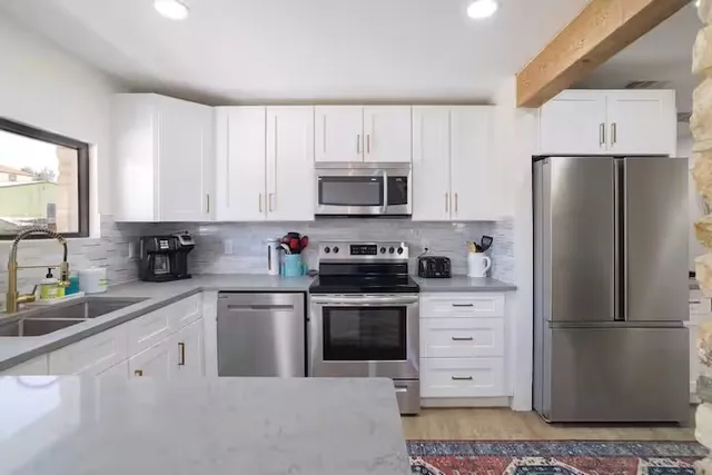 a kitchen with cabinets stainless steel appliances and a window