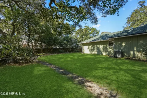 a view of a white house with a big yard and large trees