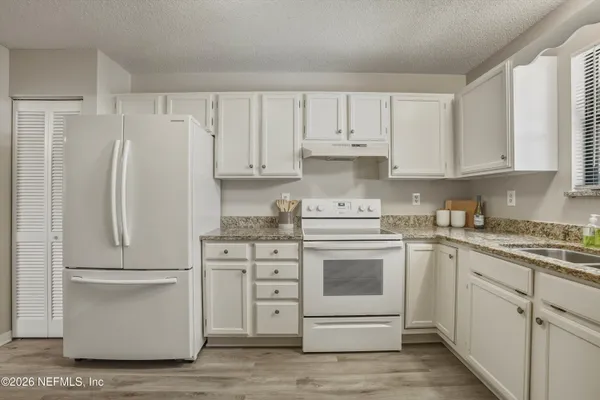 a kitchen with granite countertop white cabinets and white appliances