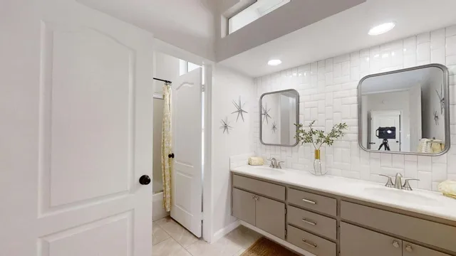 a bathroom with a double vanity sink mirror and bathtub