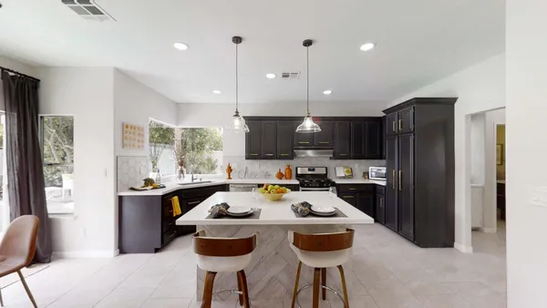 a kitchen with a refrigerator a stove a sink and a dining table with chairs