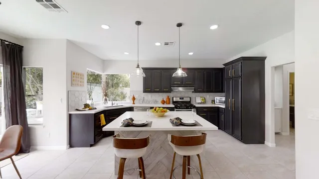 a kitchen with a refrigerator a stove a sink and a dining table with chairs