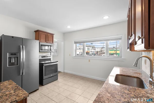 a kitchen with granite countertop a sink cabinets and stainless steel appliances