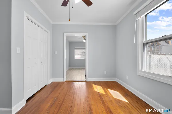 a view of an empty room with wooden floor and a window