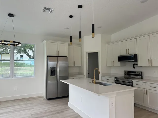 a kitchen with stainless steel appliances a refrigerator a sink a stove a microwave and wooden floor