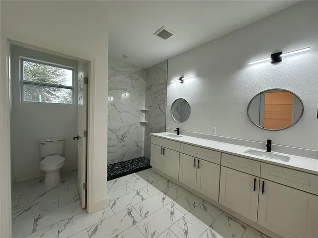 a view of a bathroom with 2 sink toilet and a mirror