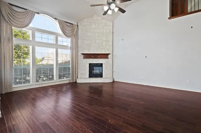 a view of an empty room with a window and wooden floor