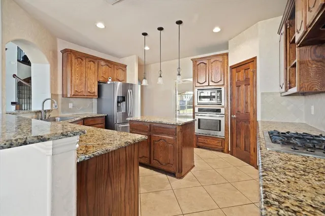 a kitchen with stainless steel appliances granite countertop a refrigerator and a stove top oven