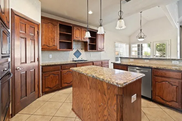 a kitchen with stainless steel appliances granite countertop a sink a stove and a wooden cabinets