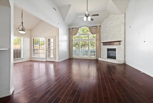 an empty room with wooden floor fireplace and windows