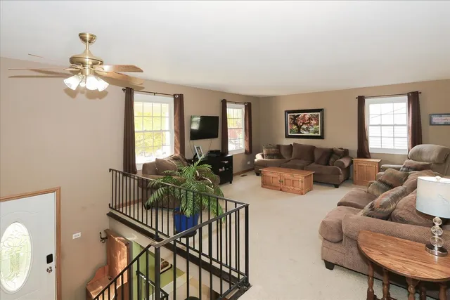 a living room with furniture a chandelier fan and a window