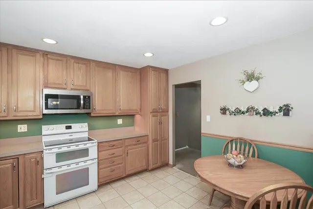 a kitchen with stainless steel appliances a microwave a sink a stove a table and chairs