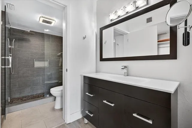 a bathroom with a sink a toilet a mirror and shower