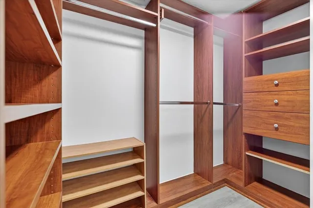 a view of walk in closet with clothes and shoes