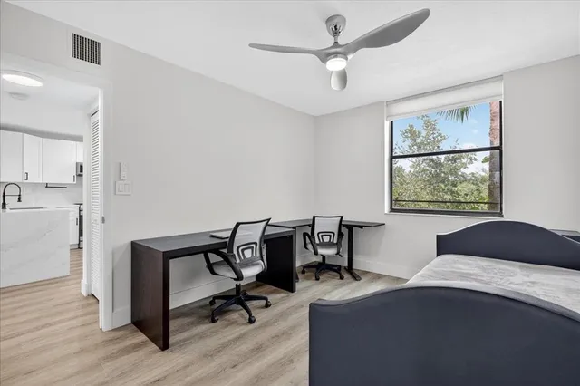 a bedroom with a bed a desk and chair with wooden floor