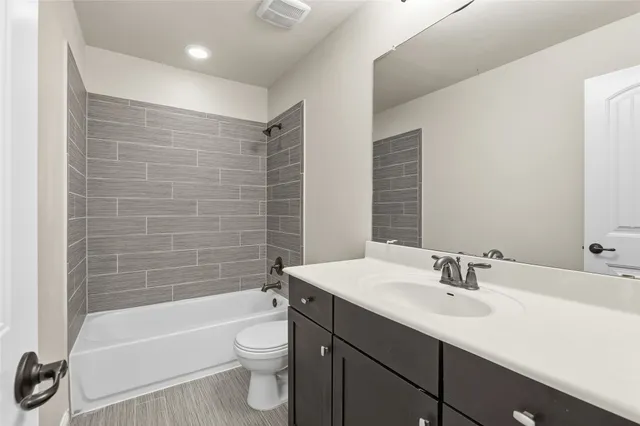 a bathroom with a bathtub shower sink vanity mirror and toilet