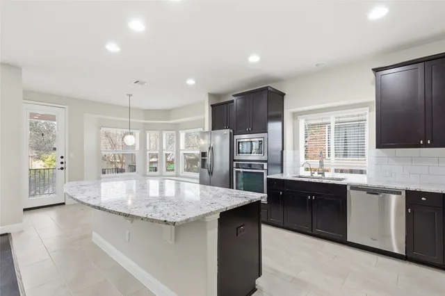a large kitchen with granite countertop a large counter top appliances and cabinets