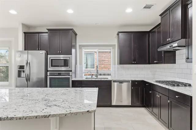 a kitchen with stainless steel appliances granite countertop a stove a sink and a refrigerator