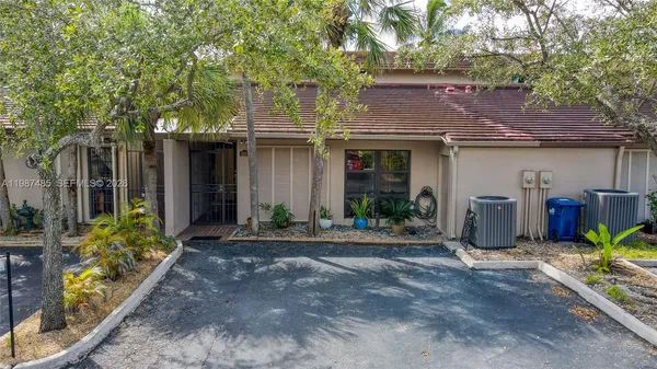 a view of a house with potted plants and a large tree