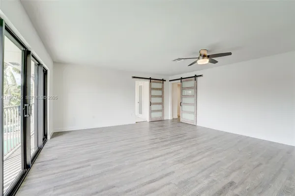 a view of an empty room with wooden floor and closet