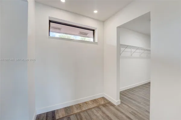 a view of an empty room with wooden floor and a window