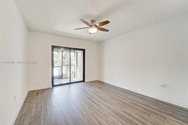 an empty room with wooden floor closet and windows