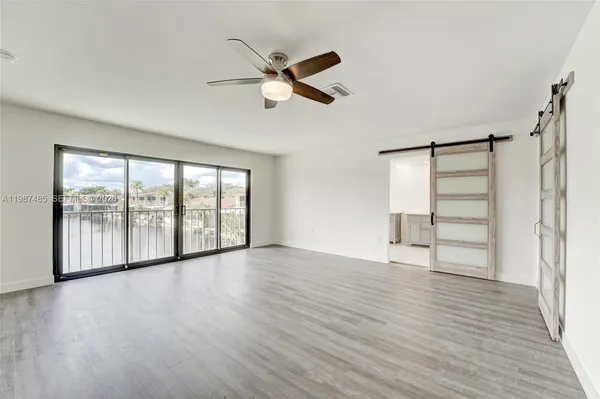 a view of an empty room with a window and wooden floor
