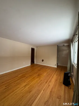 a view of empty room with wooden floor and fireplace