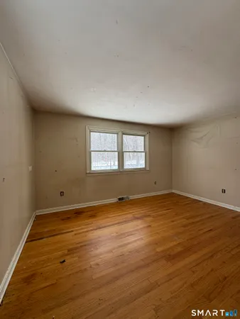 a view of an empty room with wooden floor and a window