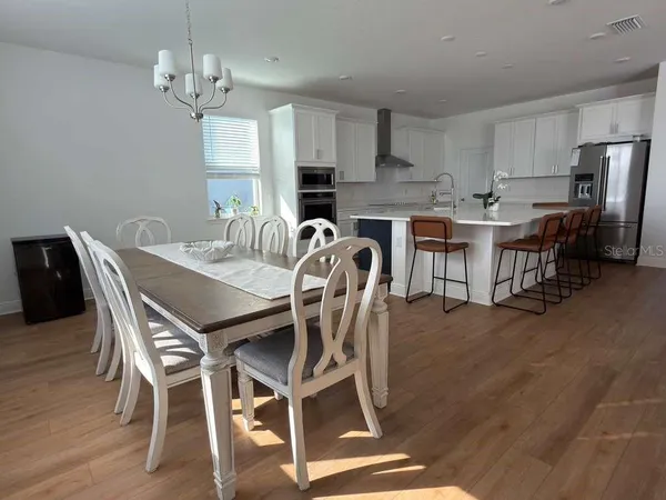 a open kitchen with stainless steel appliances granite countertop a table chairs and a wooden floors