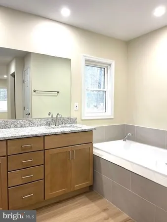 a bathroom with a granite countertop bathtub sink vanity and mirror