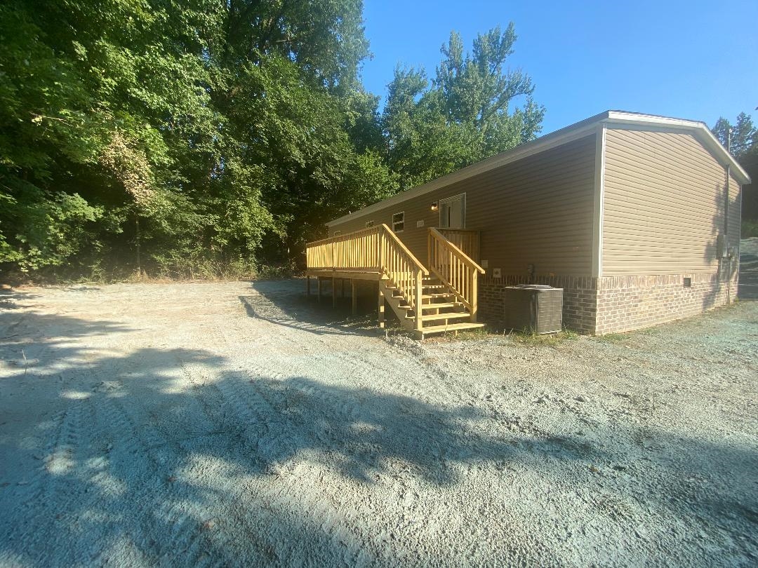 106 Simmons Road Munford, TN 38058 - Photo 24 of 30 Exterior featuring beige siding, brick-finish foundation, and a new wood deck with stairs