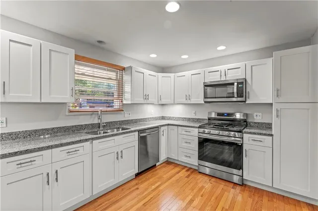 a kitchen with stainless steel appliances granite countertop white cabinets granite counter tops and a window