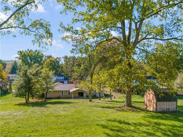 a front view of a house with a yard and trees
