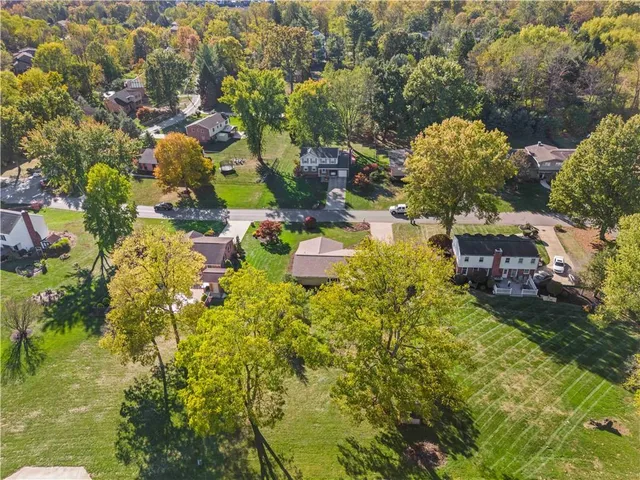 an aerial view of residential houses with outdoor space and trees