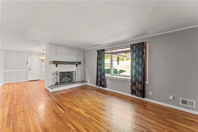 a view of empty room with a fireplace and wooden floor