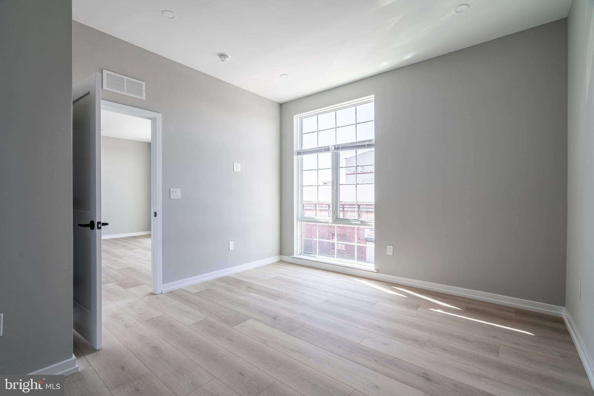 2401 Washington Avenue, Unit 3D Philadelphia, PA 19146 - Photo 16 of 18 an empty room with wooden floor cabinet and windows