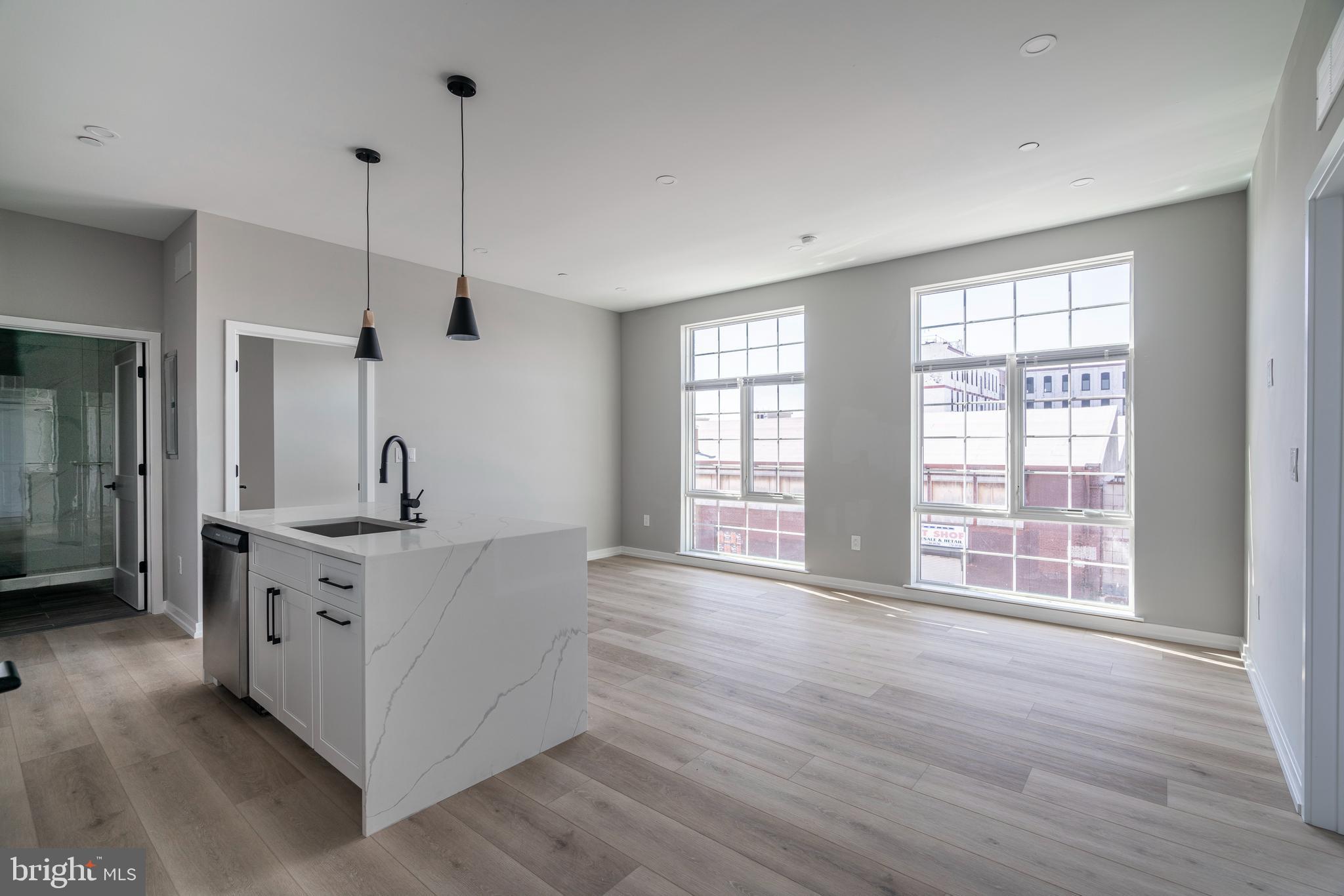 2401 Washington Avenue, Unit 3D Philadelphia, PA 19146 - Photo 2 of 18 a large kitchen with stainless steel appliances a large counter top a sink a window and wooden floor