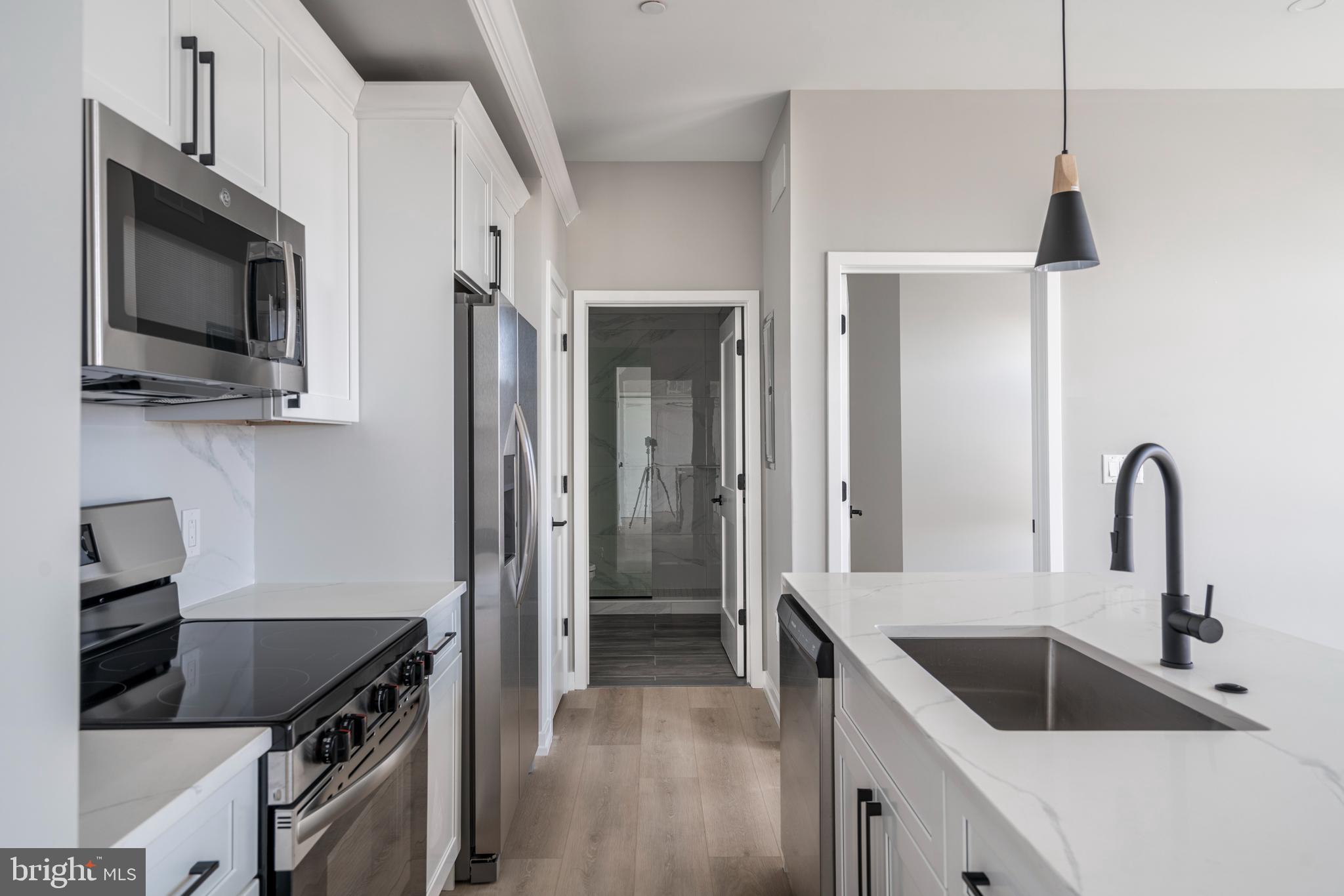 2401 Washington Avenue, Unit 3D Philadelphia, PA 19146 - Photo 5 of 18 a kitchen with stainless steel appliances granite countertop a sink and a stove top oven with wooden floor