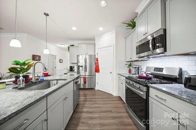 a kitchen with stainless steel appliances granite countertop a sink stove and cabinets