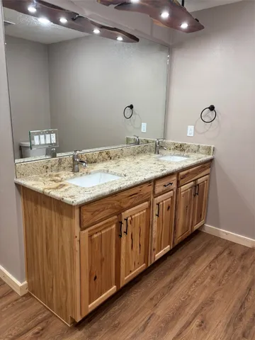 a bathroom with a granite countertop double vanity sink and mirror