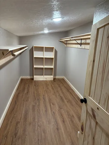 a view of empty room with wooden floor and window
