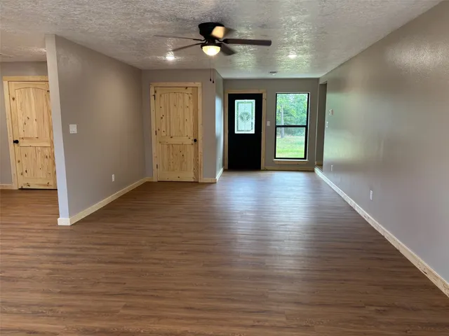 a view of an empty room with window and wooden floor