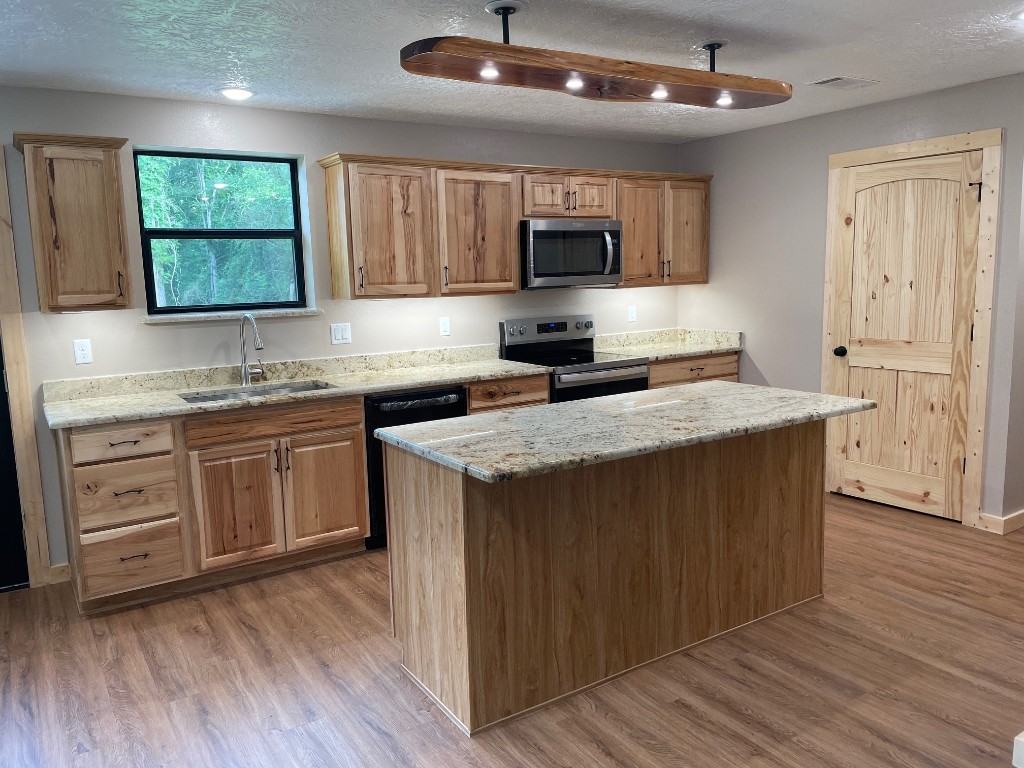 207 George Wilson Road Huntsville, TX 77320 - Photo 9 of 26 a kitchen with stainless steel appliances granite countertop a sink stove and refrigerator