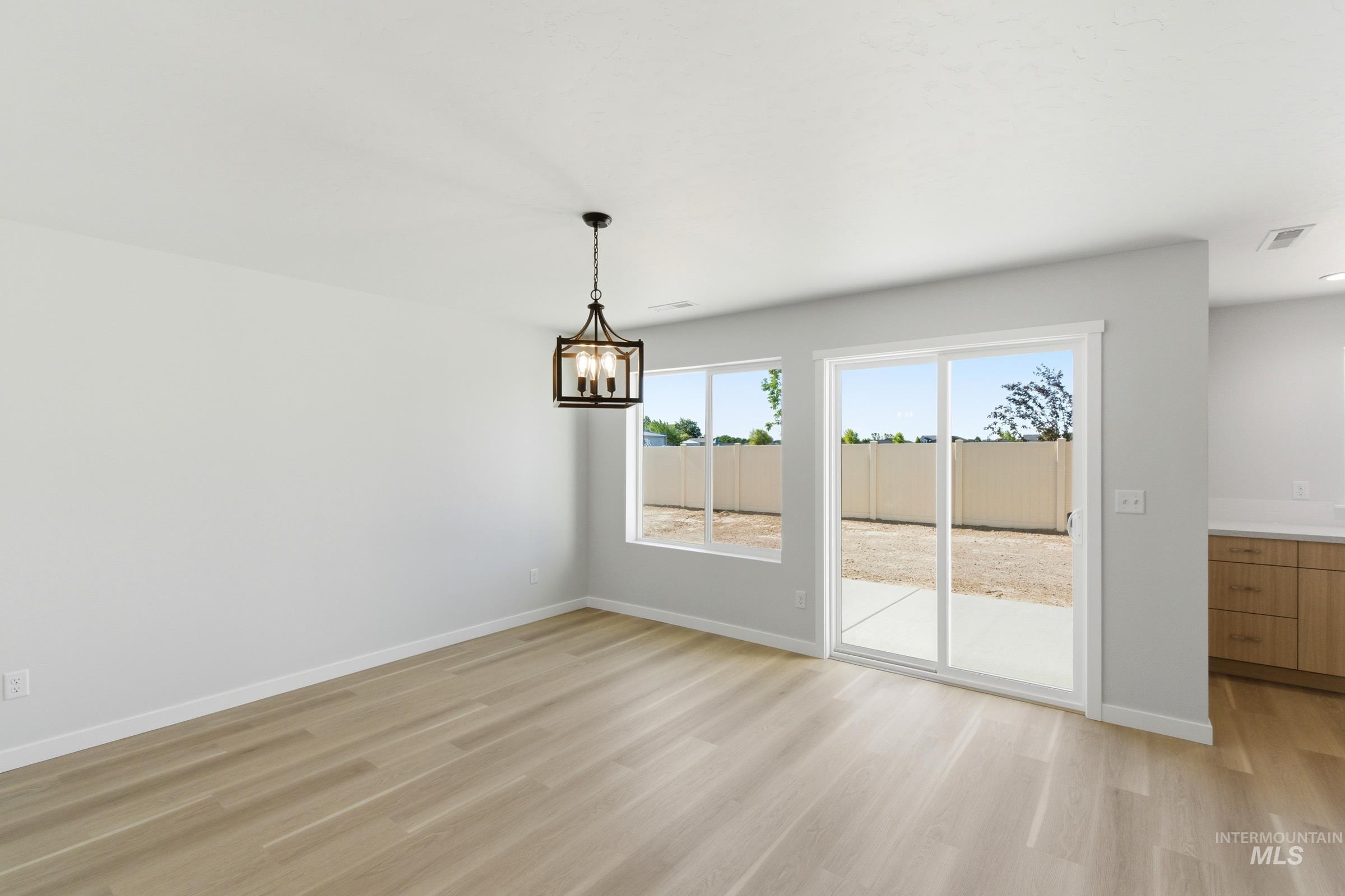13677 Redway Court Caldwell, ID 83607 - Photo 9 of 35 Open-concept dining area featuring wood-finish flooring, a modern linear chandelier, and a sliding glass door providing direct access to the backyard