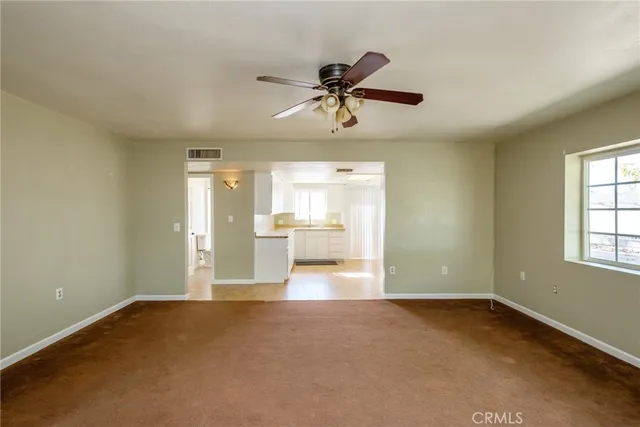 a view of a room with window a ceiling fan and wooden floor